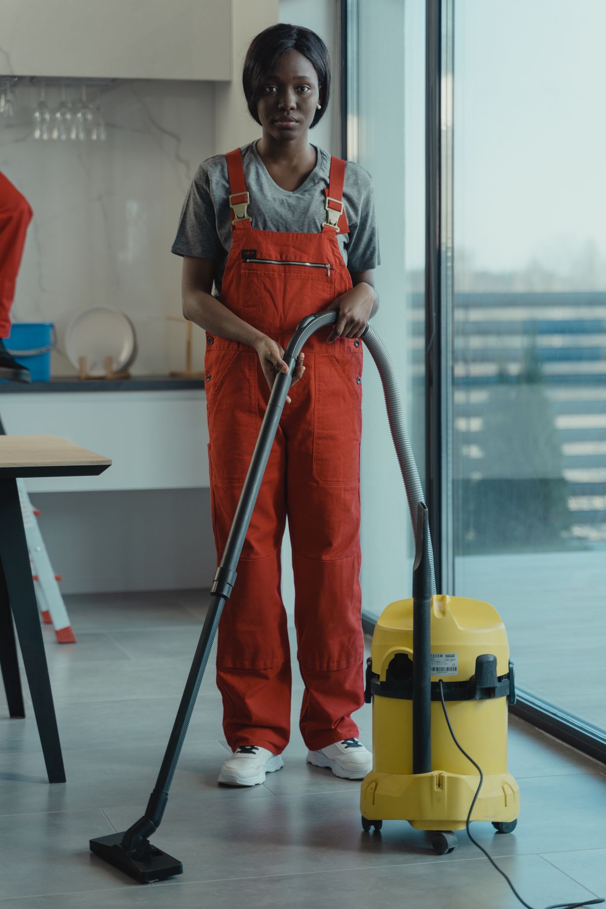 A cleaner with a vacuum in a bright kitchen