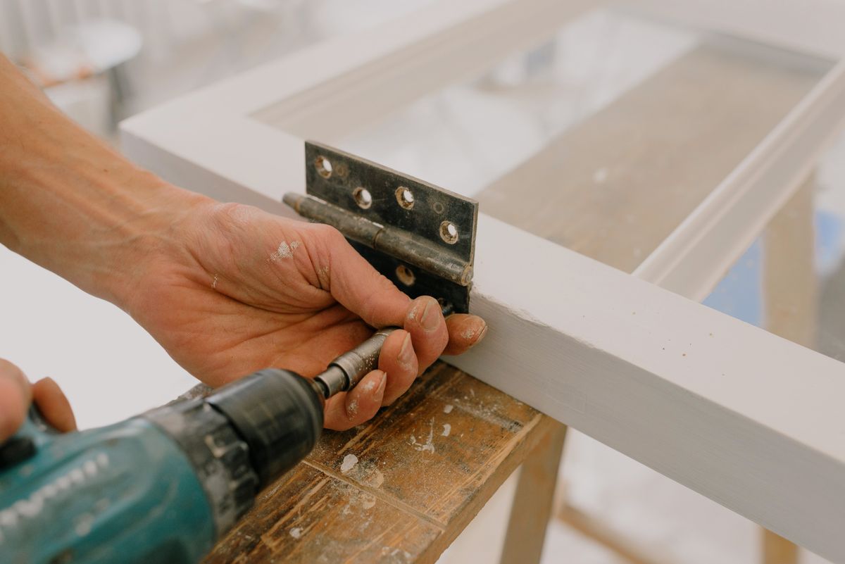 Hands carefully repairing a door hinge
